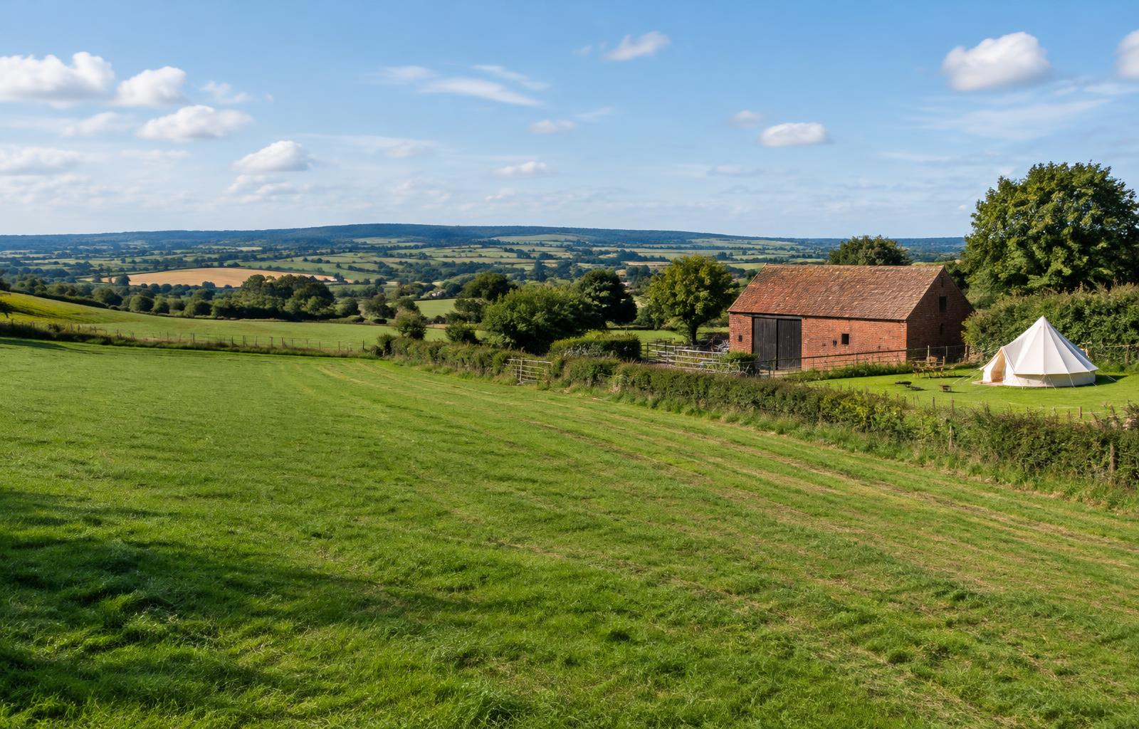 Open farmland with a traditional barn and a bell tent